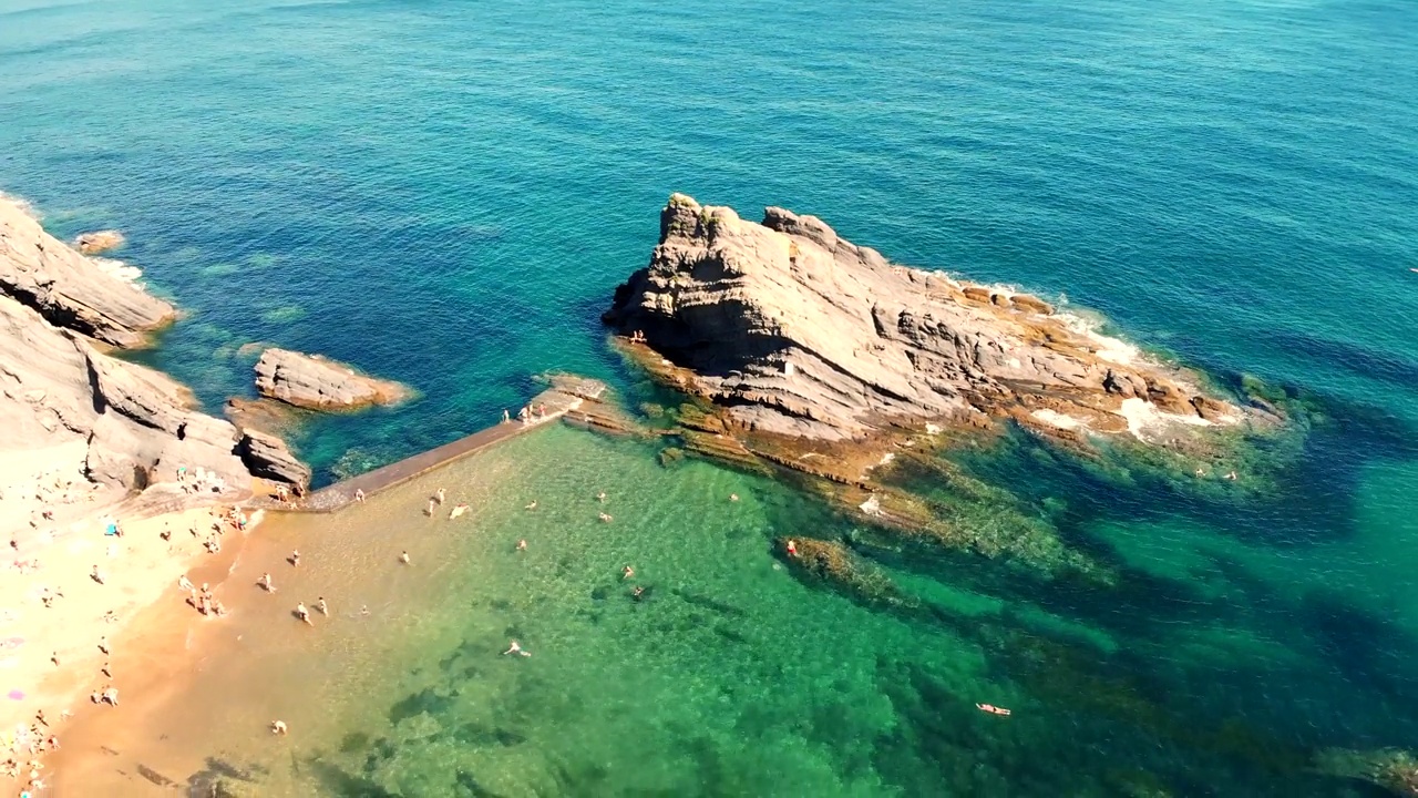 平静的海滩，岩层和清澈的海水。人们喜欢阳光。视频素材