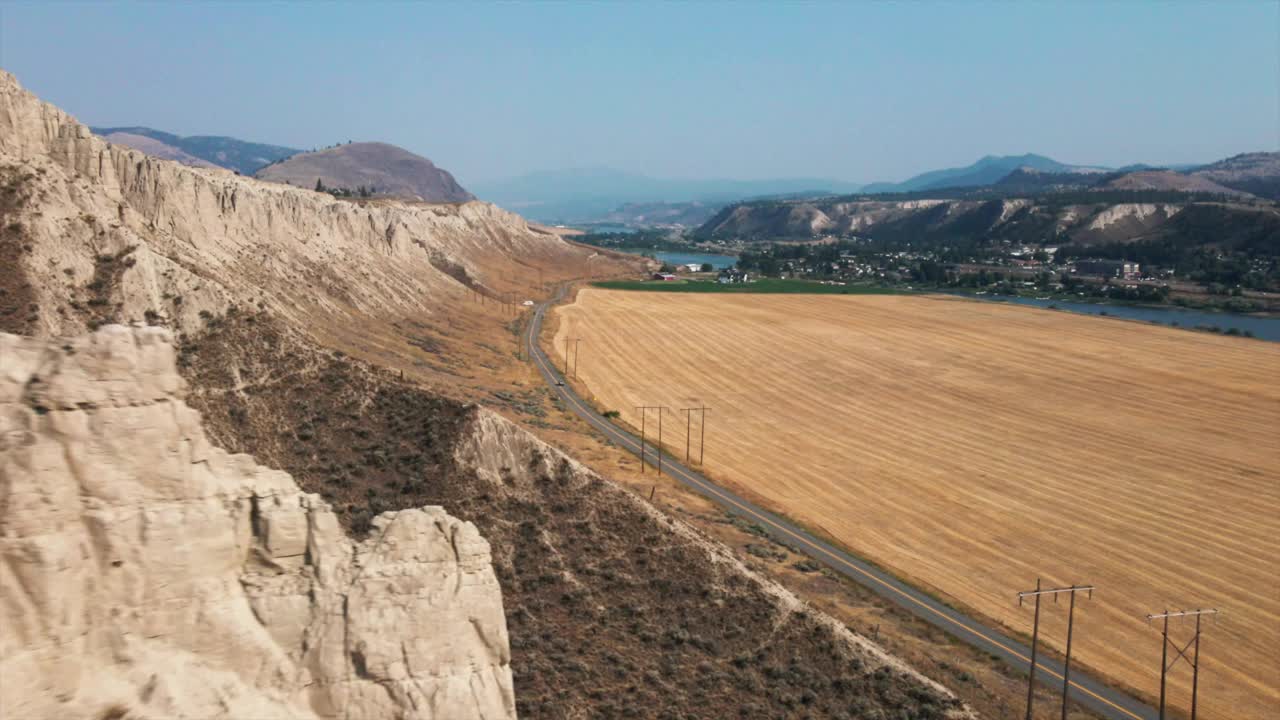 山野之间的公路鸟瞰图，远处有小山。美丽的无人机镜头下的山区景观明亮的蓝天视频素材