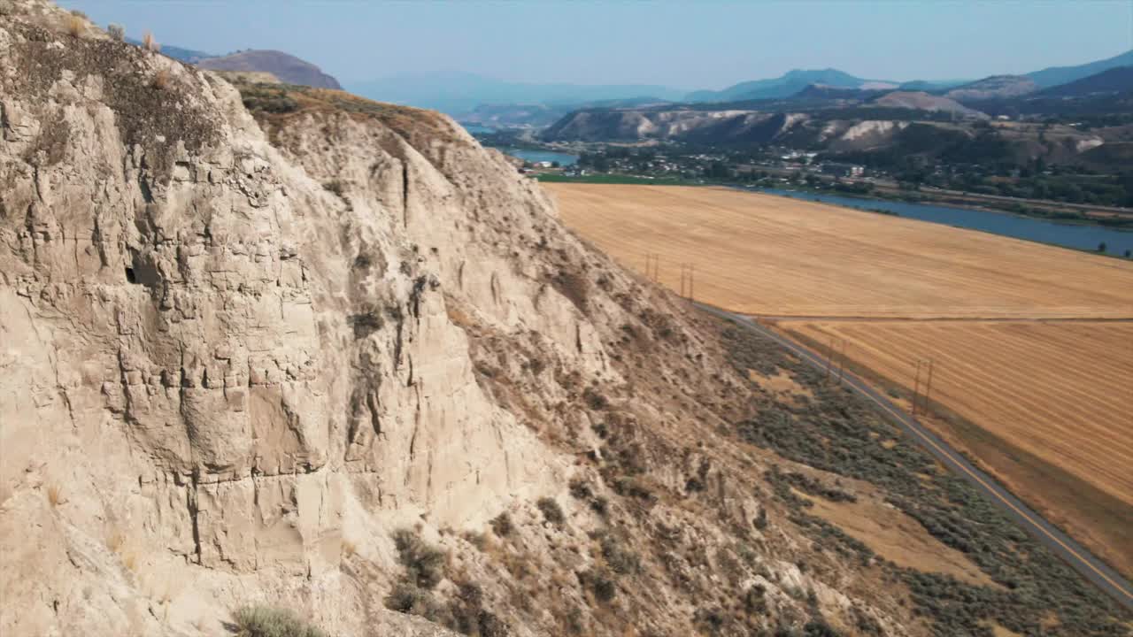 鸟瞰美丽的山景，以田野和道路为背景。蓝天下令人惊叹的山地景观的宁静无人机镜头。岩石的形成视频素材