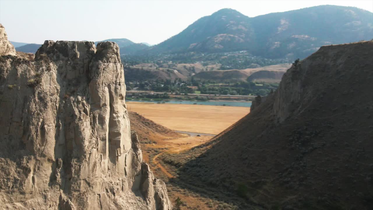 美丽的峡谷鸟瞰图，远处有山脉和多云的天空。以山区景观为背景的悬崖惊人的无人机镜头视频素材