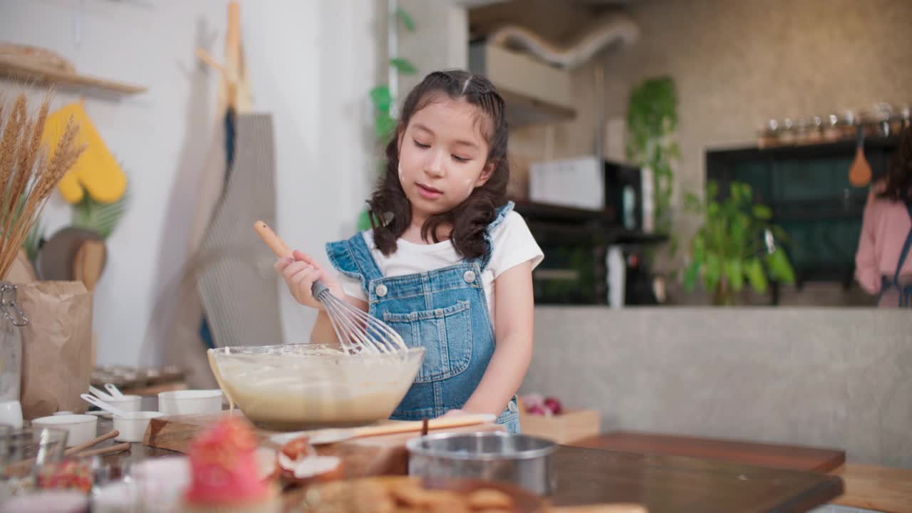 女孩们喜欢在碗里搅拌面团。视频素材