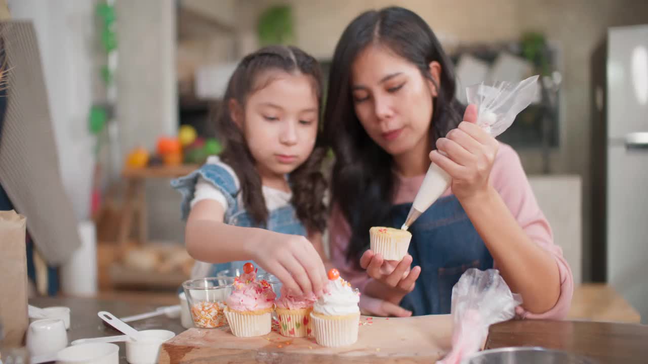 妈妈在教女儿怎么做小蛋糕。视频素材