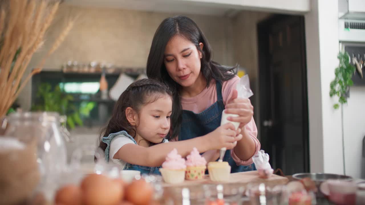 妈妈在教女儿怎么做小蛋糕。视频素材