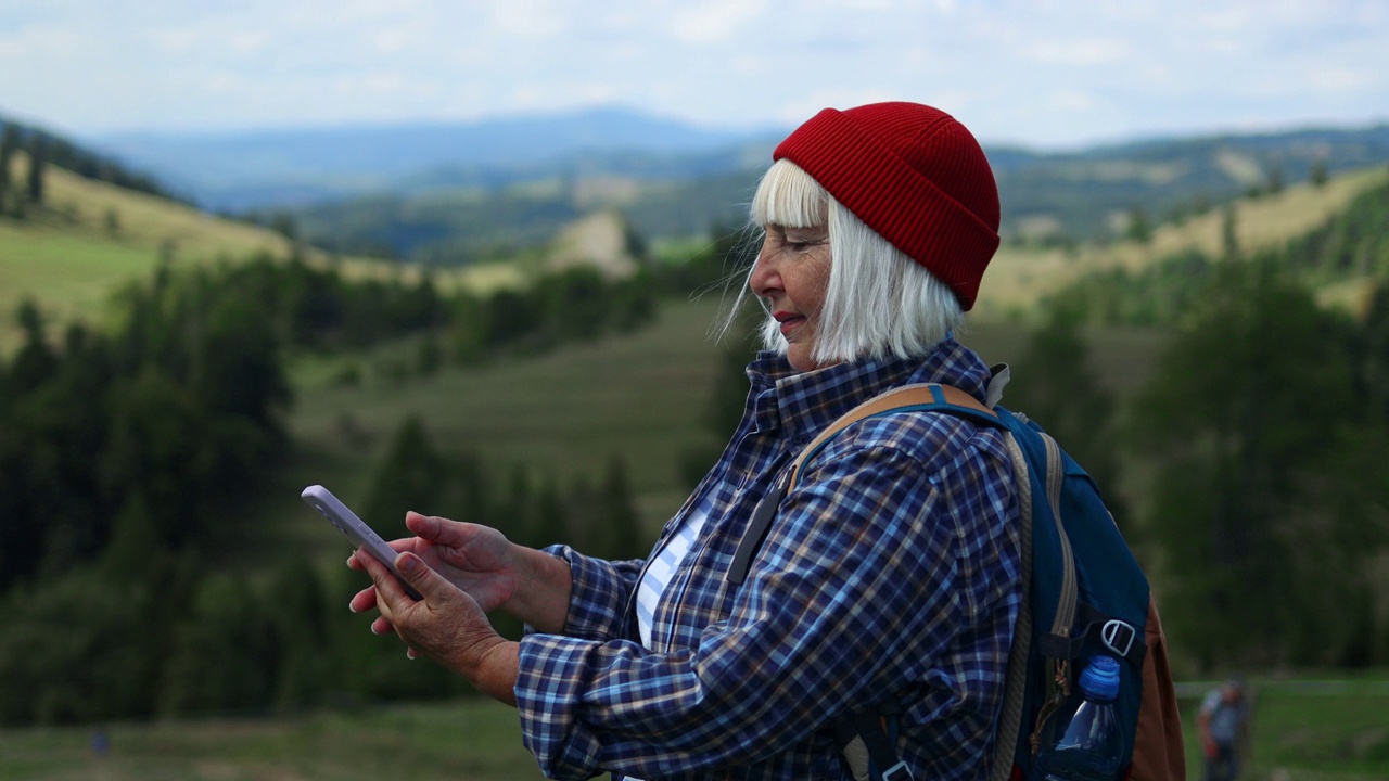 女子徒步旅行者，徒步背包客露营与她的手机相机在山顶在阳光灿烂的日子。美丽的山景。远足、徒步旅行。4 k视频素材