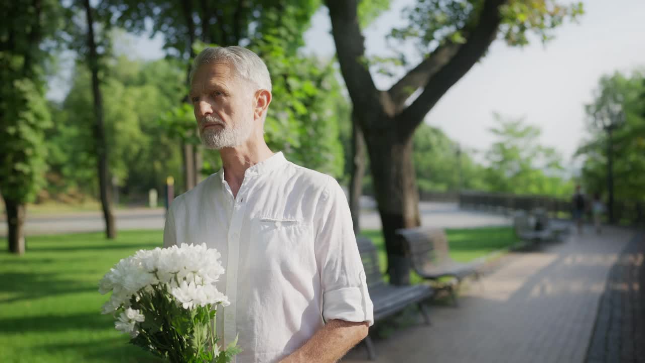 漂亮的年长的男子花等待他的约会在城市在公园，约会生活视频素材