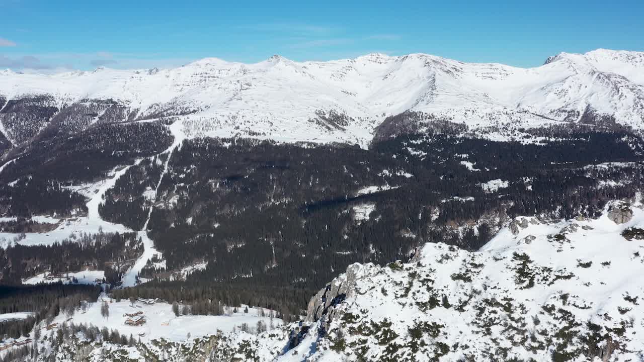 这是意大利北部普斯特里亚山谷的白云石山脉，在一个阳光明媚、寒冷的冬日里，周围是黑暗的森林。视频下载