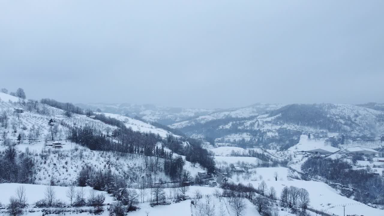 有树木和小径的雪地。山上的房子在冬天。鸟瞰图。视频素材