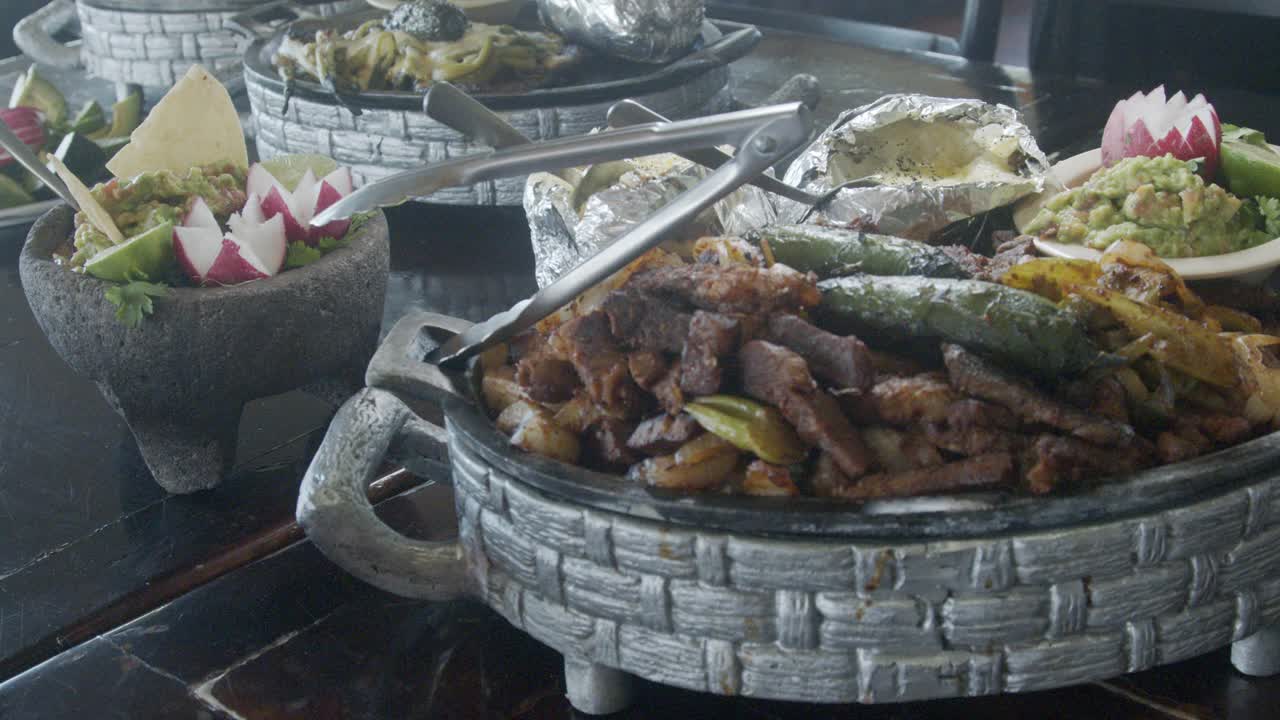 Beef Fajitas in a Pewter Tray With Guacamole, Radish, Jalapeño Pepper and Baked Potato in a Fancy Mexican Restaurant in Tijuana, Baja California Norte Mexico视频素材