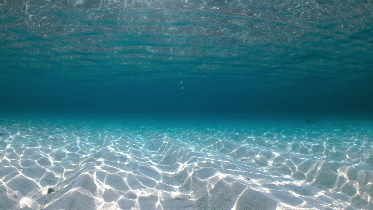 透明的海洋有波浪，阳光灿烂的水下有沙滩视频素材