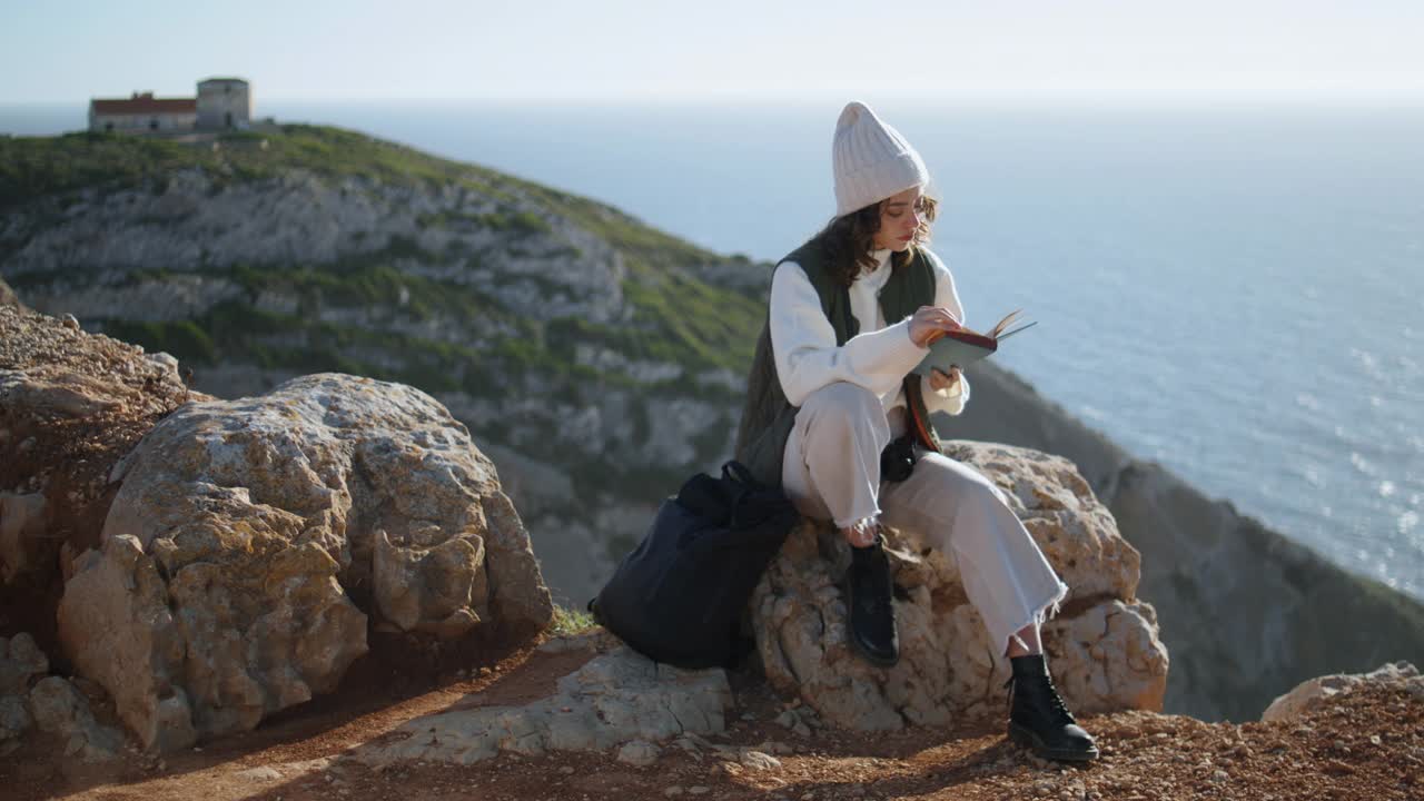 浪漫的女孩在落基山上看书。宁静的游客休息海洋悬崖视频素材