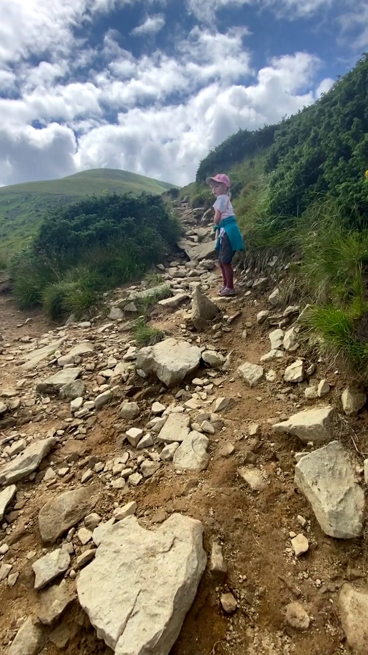 可爱的小女孩沿着山间小路爬向山顶视频素材