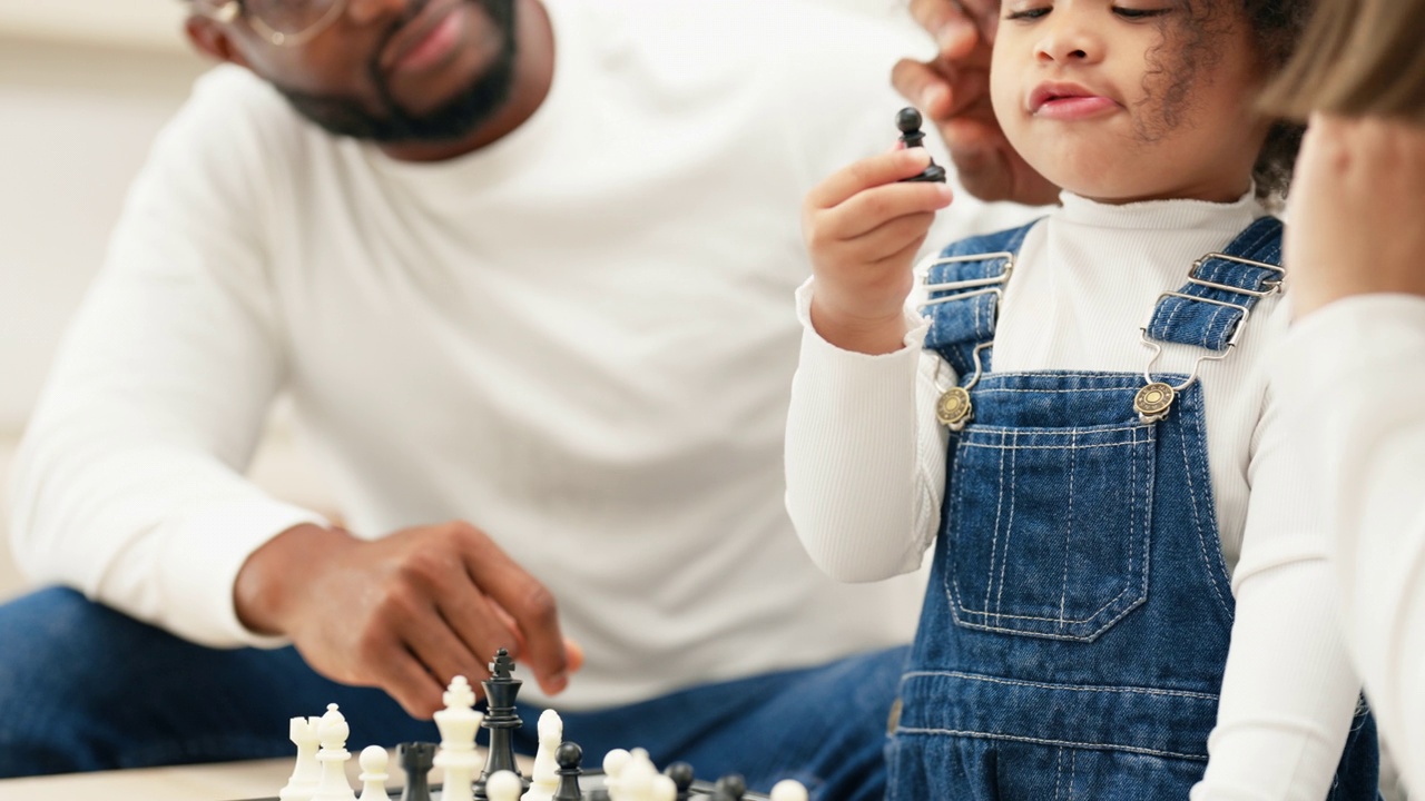 多种族新人父母在客厅和女儿下棋的特写镜头。视频素材