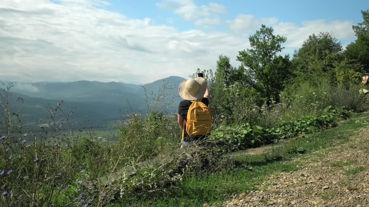 女旅游博主在绿色风景的山顶上用手机自拍视频素材