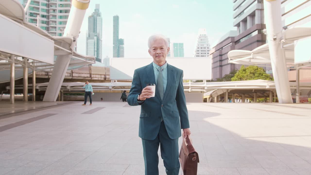 一个亚洲年长的商务男子穿着西装，拿着咖啡杯行走视频下载