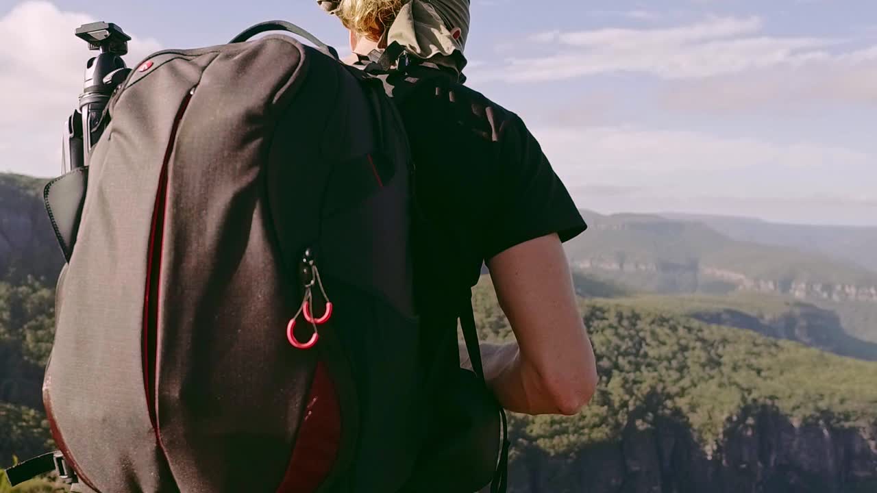 年轻男子在背包旅行时在山的边缘拍摄风景照片视频素材