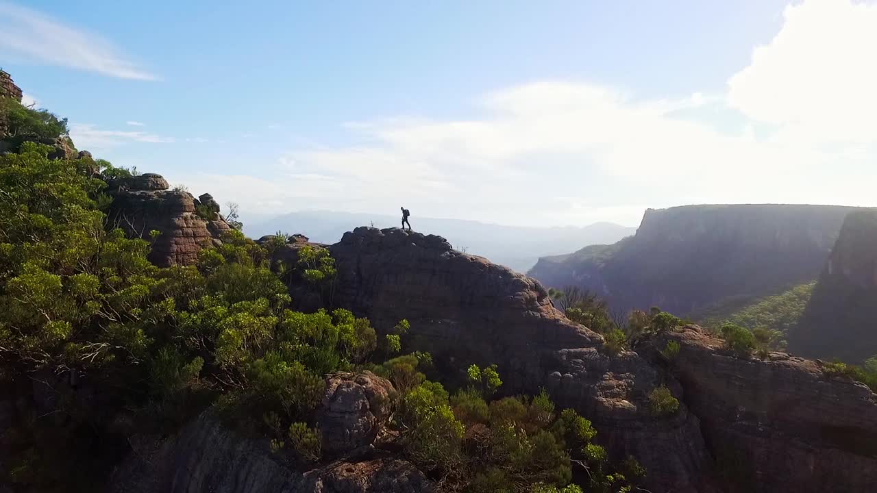 年轻男子背着摄影装备，在阳光明媚的日子里在山上360度全景视频素材