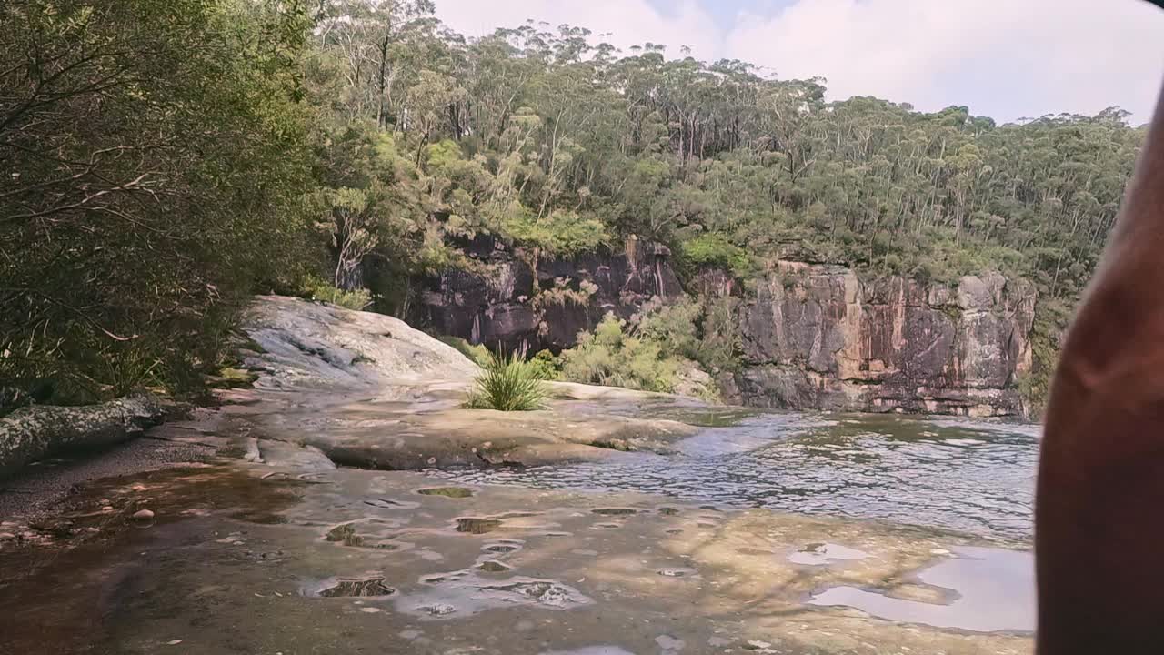 一个年轻人正在拍摄山上的瀑布和湍急的溪流视频素材