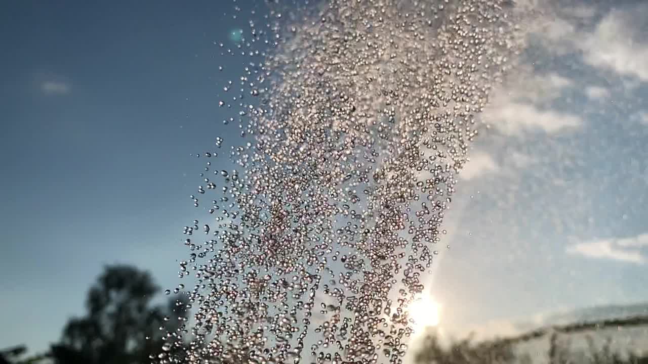 雄伟的视频动画裁剪的水淋浴雨流从洒水车，空气喷雾器，粉碎机对树木和天空视频素材