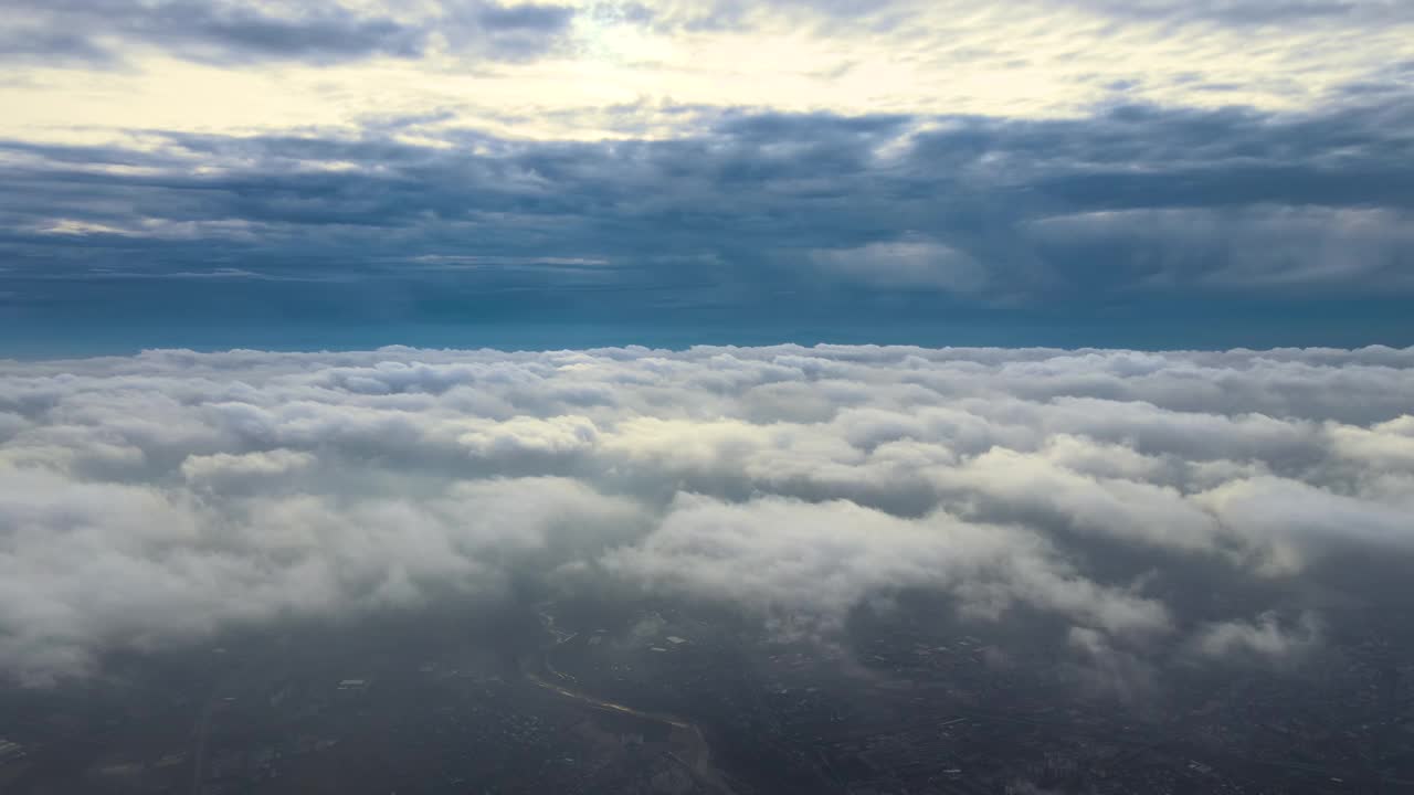 高空鸟瞰图，远处的城市被暴雨前形成的蓬松积云覆盖。多云景观的飞机视角视频素材