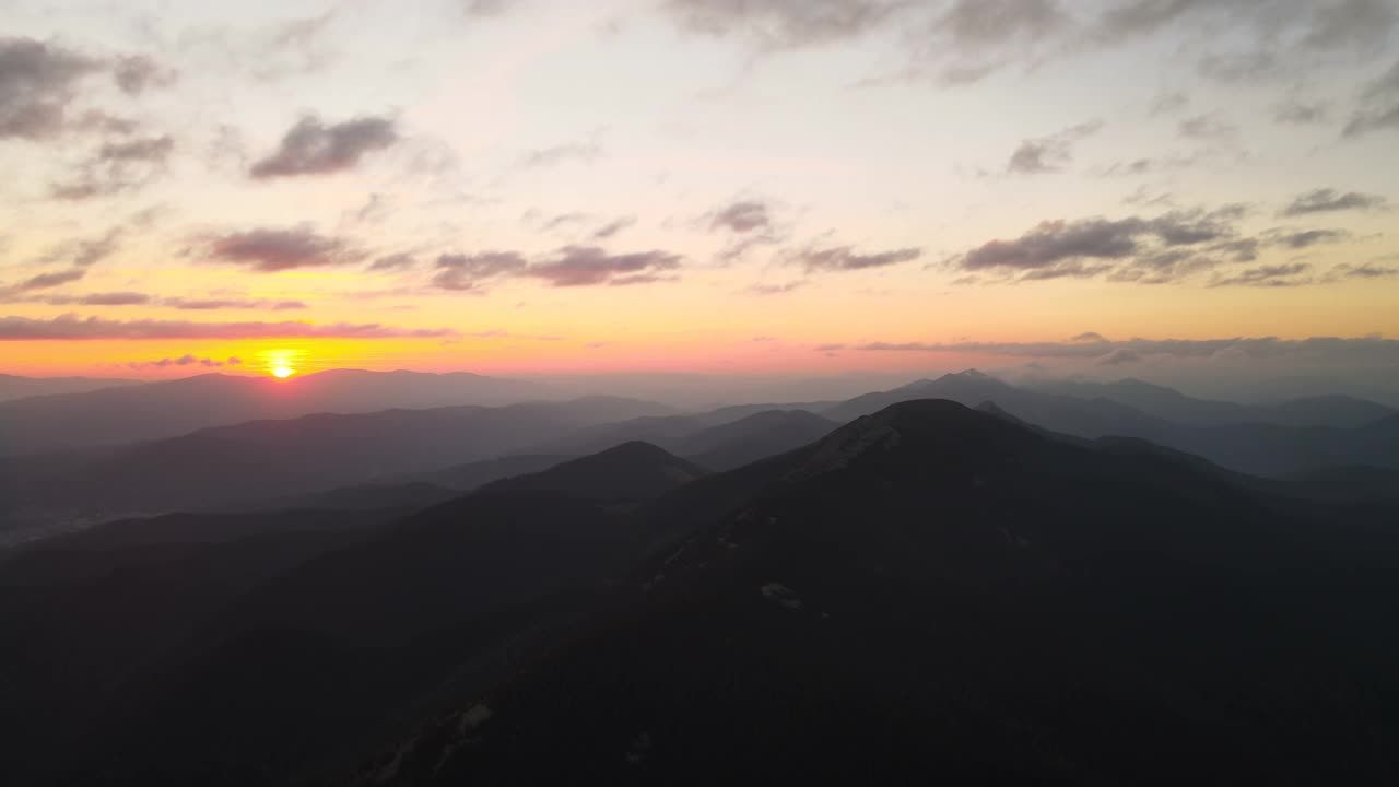 在明亮的日落时，高空鸟瞰有雾的夜晚与黑暗的松林。黄昏时分野山林地的迷人景色视频素材