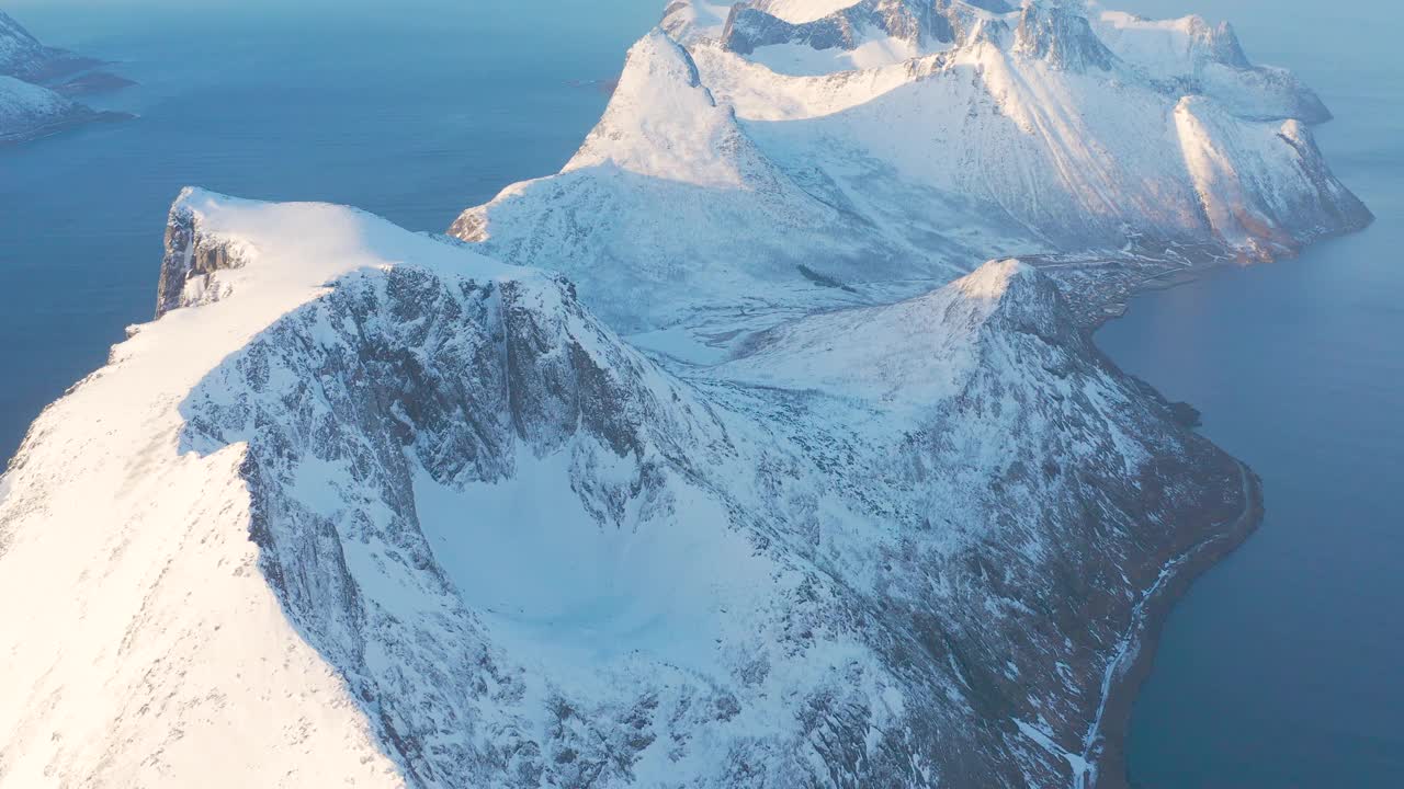 令人惊叹的鸟瞰，挪威海水中覆盖着白雪的高山岩石山峰。令人惊叹的全景峡湾景观Senja在冬季，平静的自然之美。视频素材