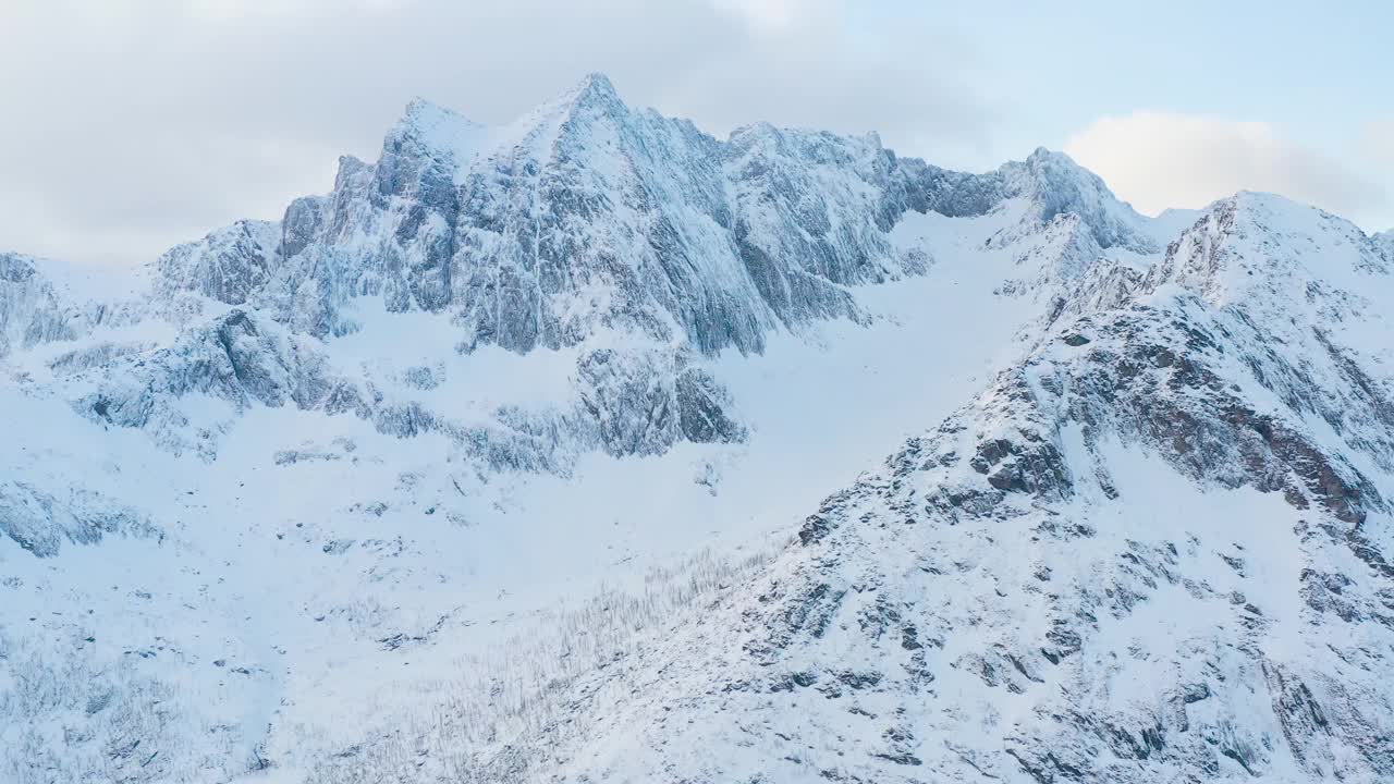 令人惊叹的鸟瞰，挪威海水中覆盖着白雪的高山岩石山峰。令人惊叹的全景峡湾景观Senja在冬季，平静的自然之美。视频素材