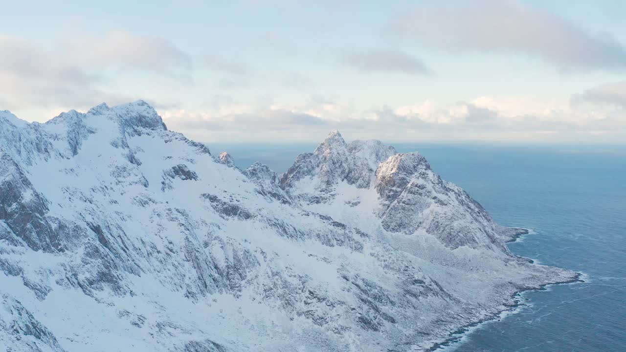 令人惊叹的鸟瞰，挪威海水中覆盖着白雪的高山岩石山峰。令人惊叹的全景峡湾景观Senja在冬季，平静的自然之美。视频素材