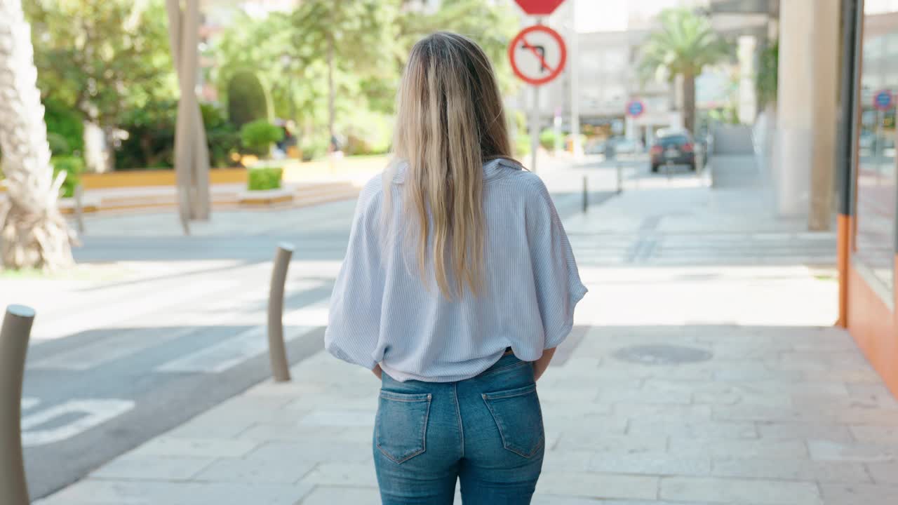 年轻的金发女子站在手臂交叉的姿态在街上视频素材