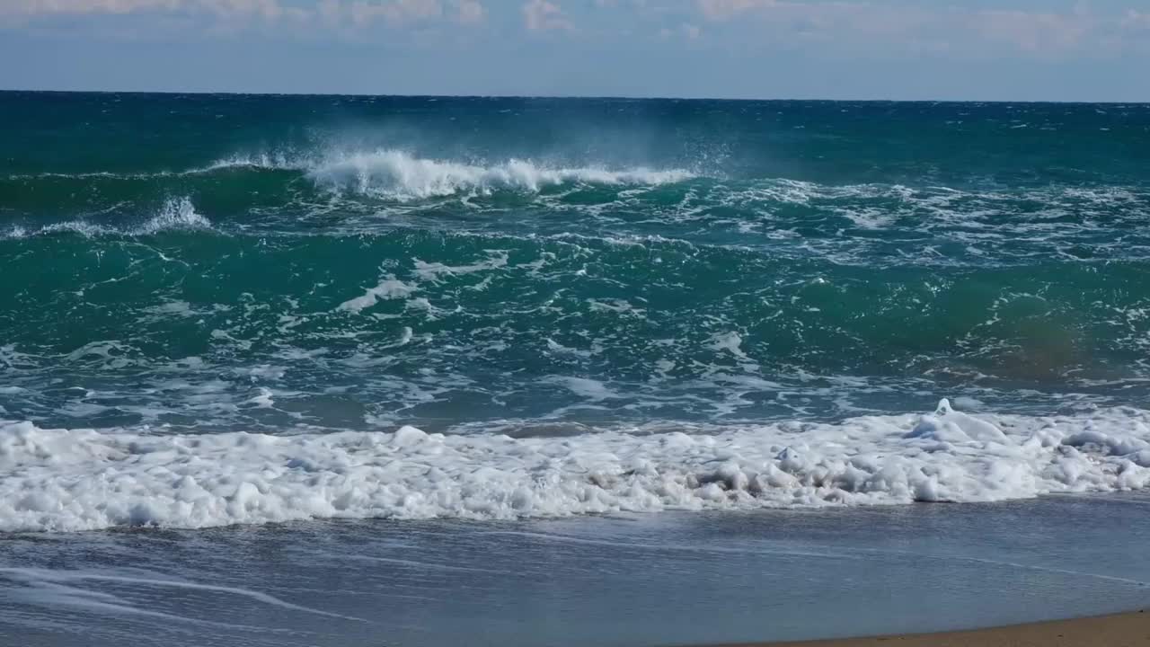 在低低的阳光下，泡沫般的海浪慢慢地向沙滩落下视频下载