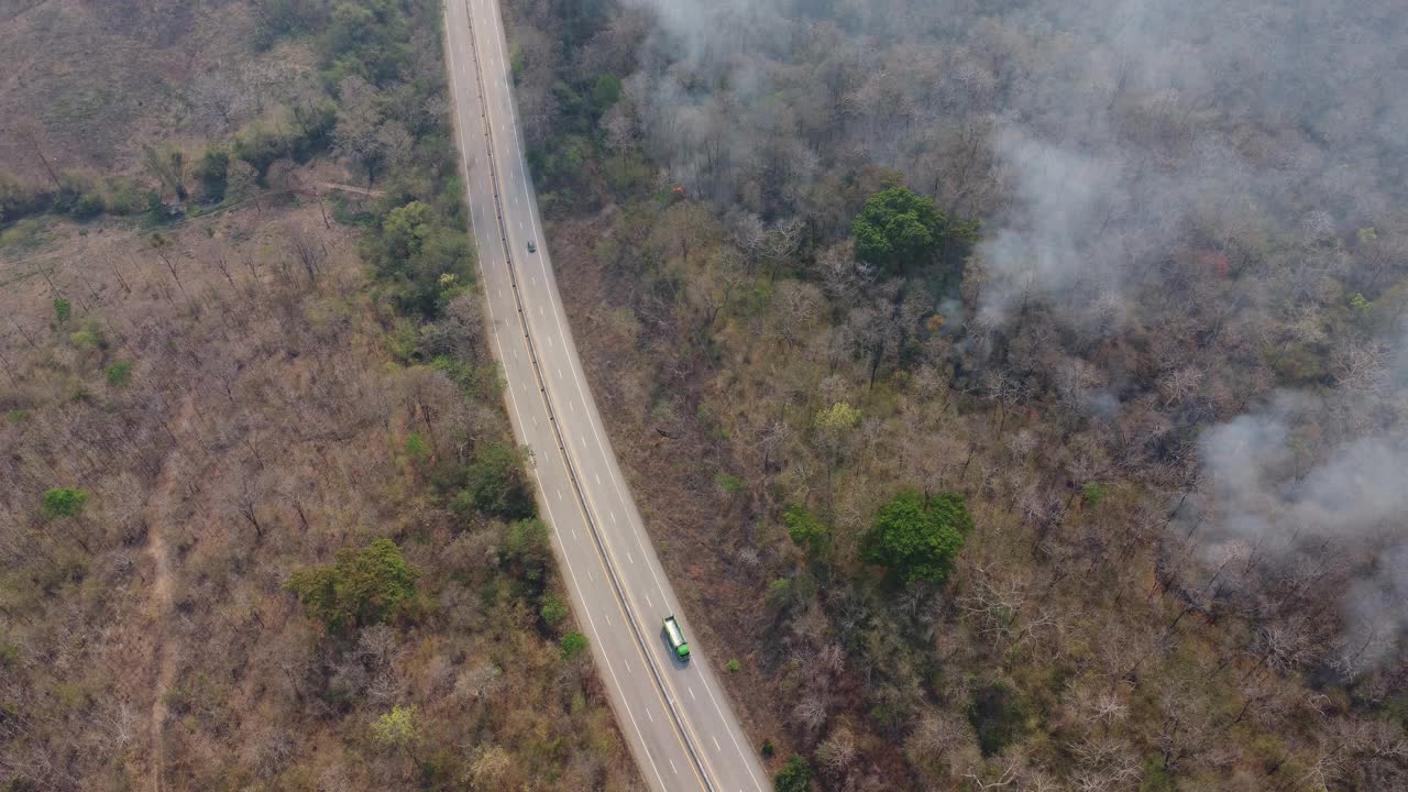 无人机拍摄的野火在森林地区燃烧，在高速公路边缘附近的树林里，天空中弥漫着黑烟。燃烧的森林。空气污染概念视频素材