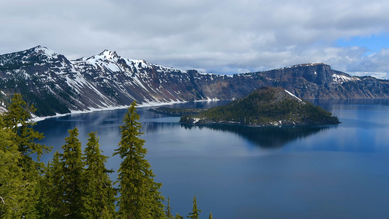 火山口湖-在一个平静的春天早晨，低云掠过蓝色的火山口湖和岩石奇才岛的延时视频。火山口湖国家公园，俄勒冈州，美国。视频下载