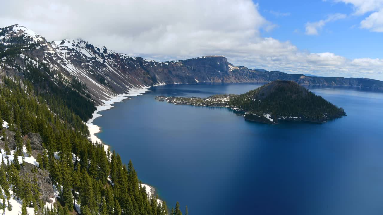 火山口湖-一个多云的春天早晨，蓝色的火山口湖和岩石奇才岛的延时全景。火山口湖国家公园，俄勒冈州，美国。视频下载