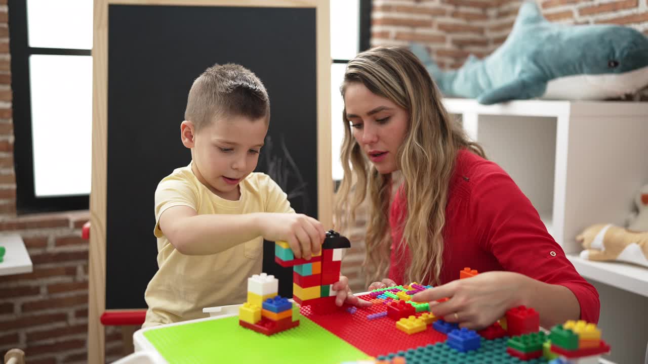 幼儿园里，老师和幼儿坐在桌子上玩积木视频素材