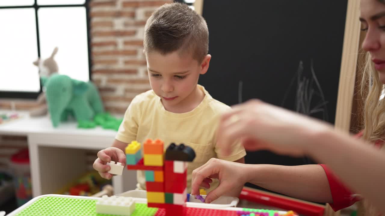 幼儿园里，老师和幼儿坐在桌子上玩积木视频素材