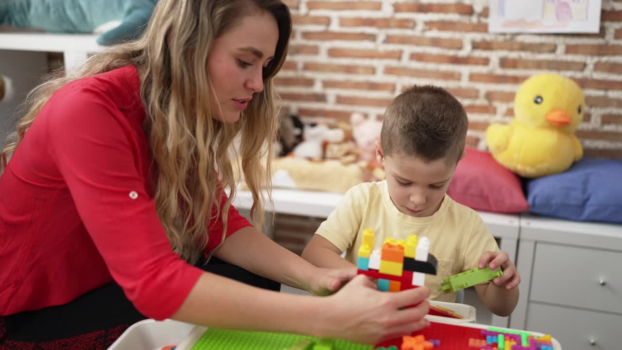 幼儿园里，老师和幼儿坐在桌子上玩积木视频素材