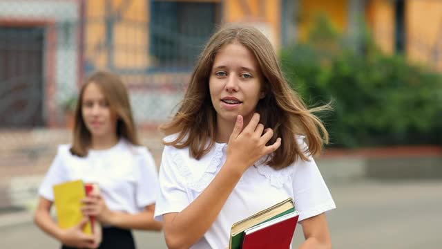 两个漂亮的少女穿着黑白制服背着书包去上学视频素材