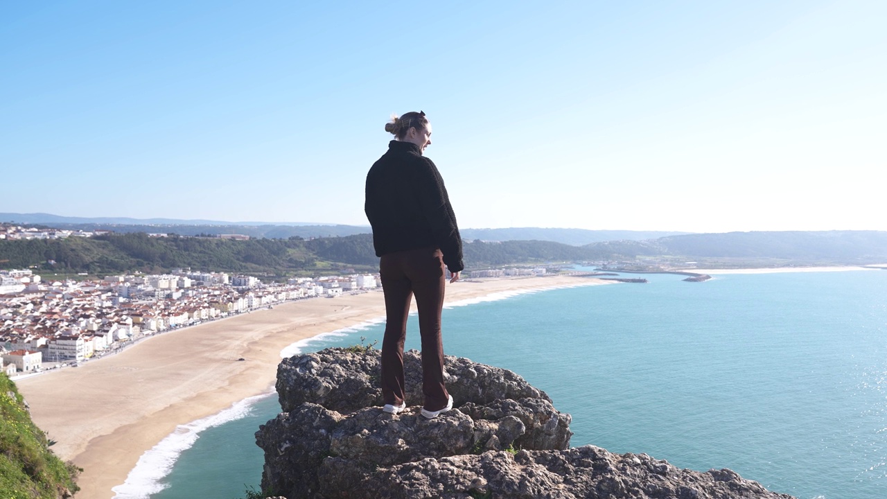 年轻女子在旅行时，从山顶上欣赏村庄的景色和大海和天空视频下载