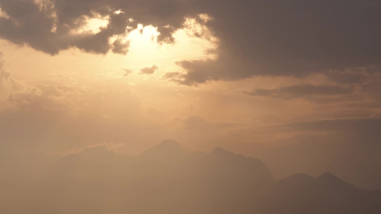 橘黄色的太阳在山上海面上飘过云霞，夕阳西下。视频素材