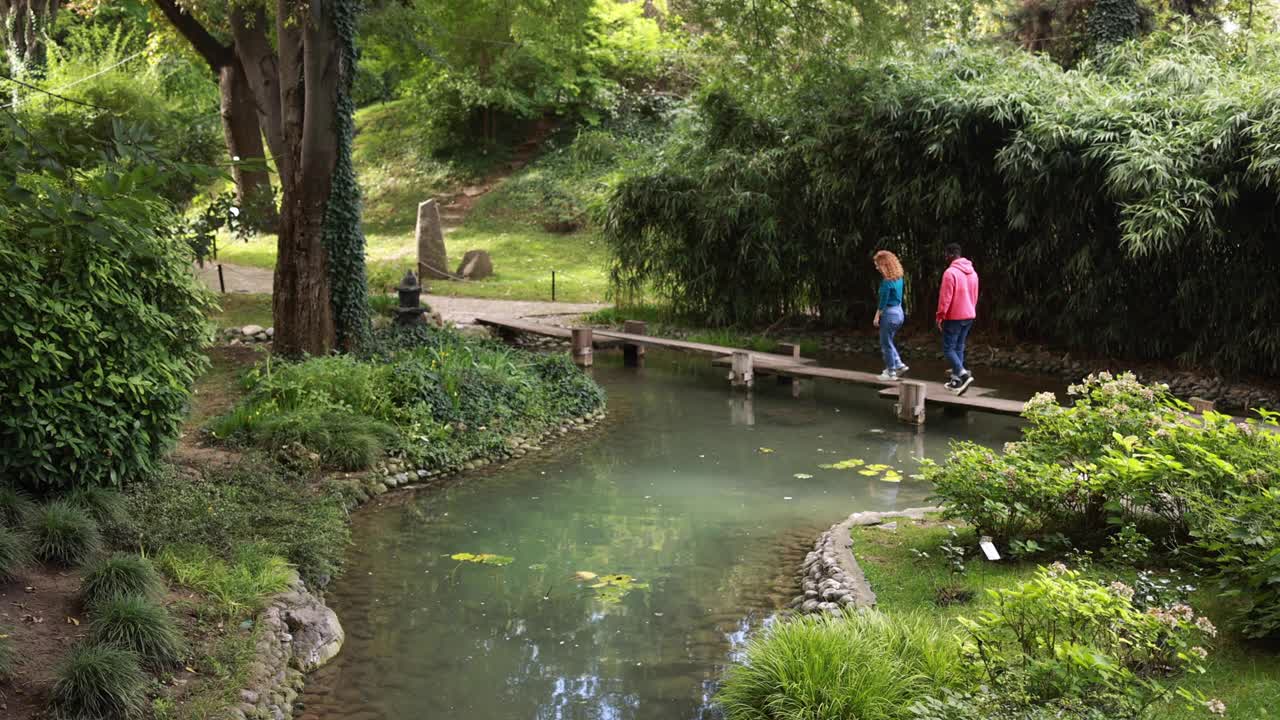 幸福的不同夫妇在公园的池塘边聊天放松。视频素材