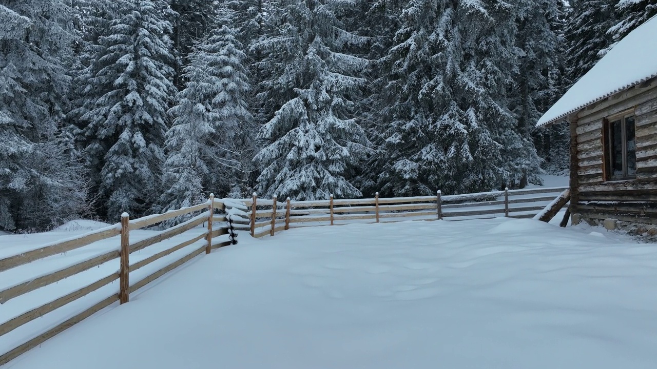 壮丽的山区冬季景观，冷杉林中幽静的小木屋在下雪时完全被雪覆盖。视频素材