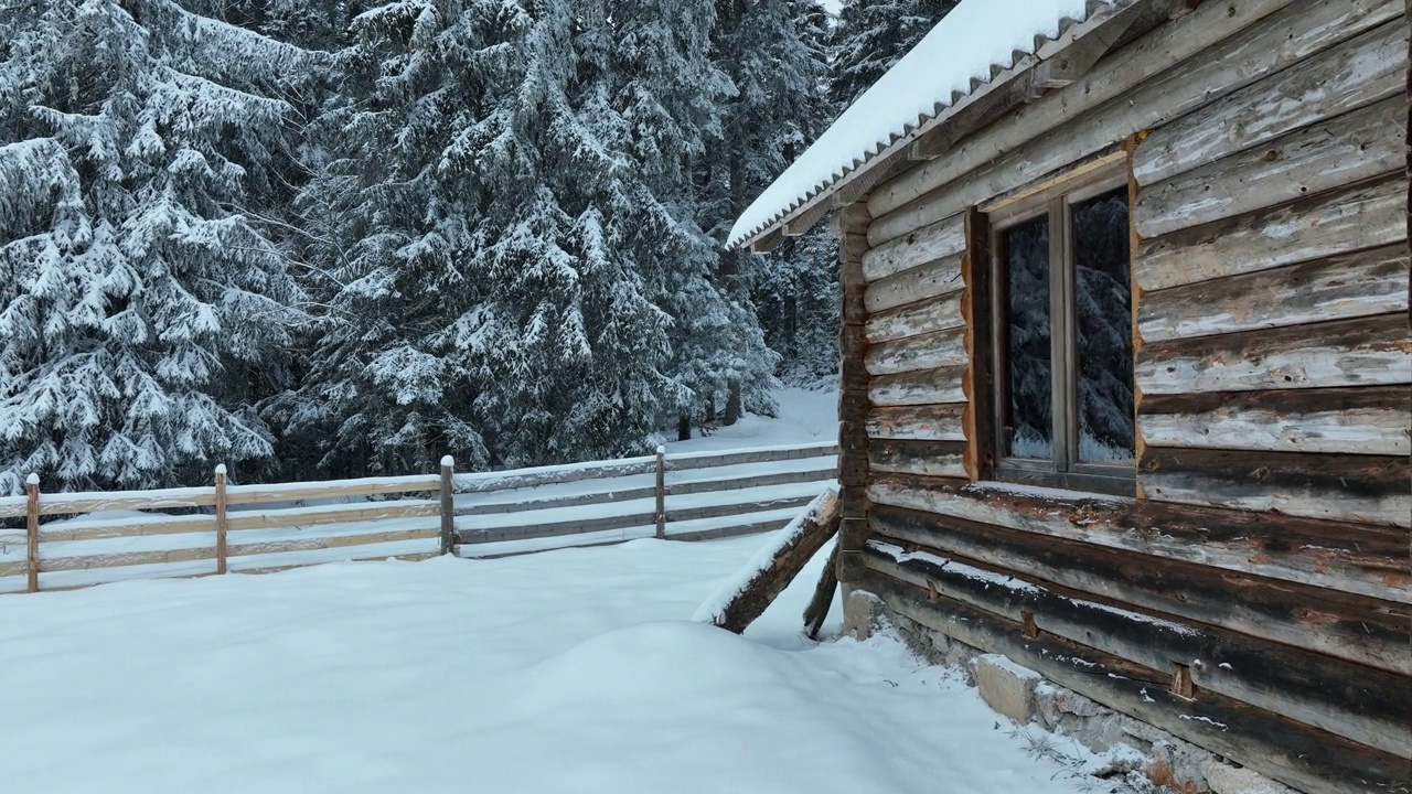 壮丽的山区冬季景观，冷杉林中幽静的小木屋在下雪时完全被雪覆盖。视频素材