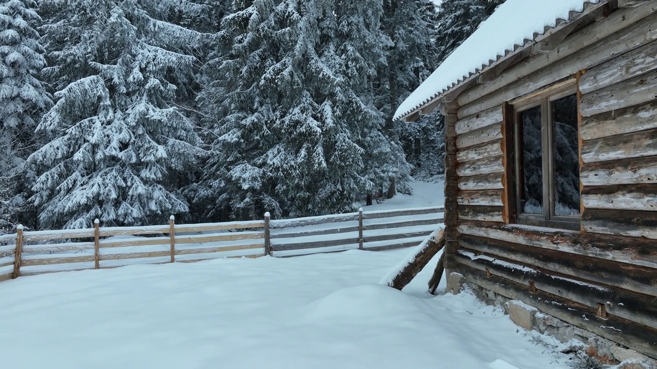 壮丽的山区冬季景观，冷杉林中幽静的小木屋在下雪时完全被雪覆盖。视频素材