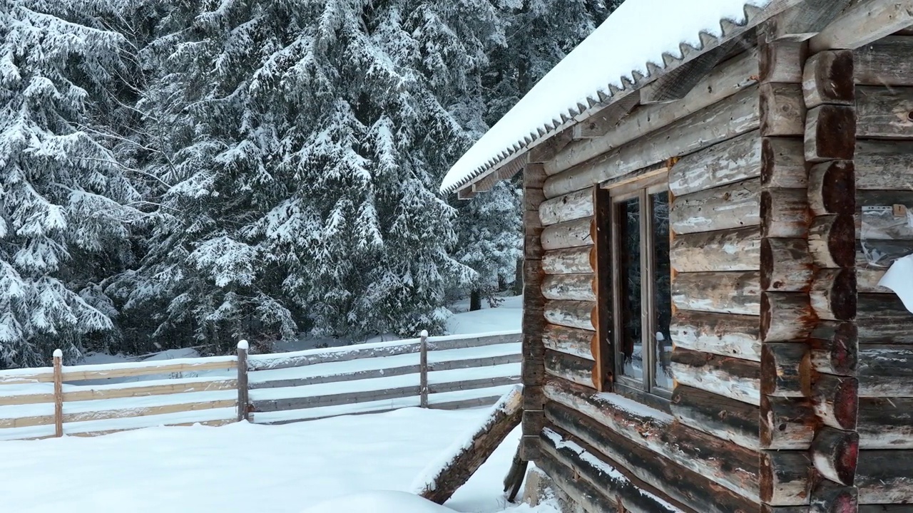 壮丽的山区冬季景观，冷杉林中幽静的小木屋在下雪时完全被雪覆盖。视频素材