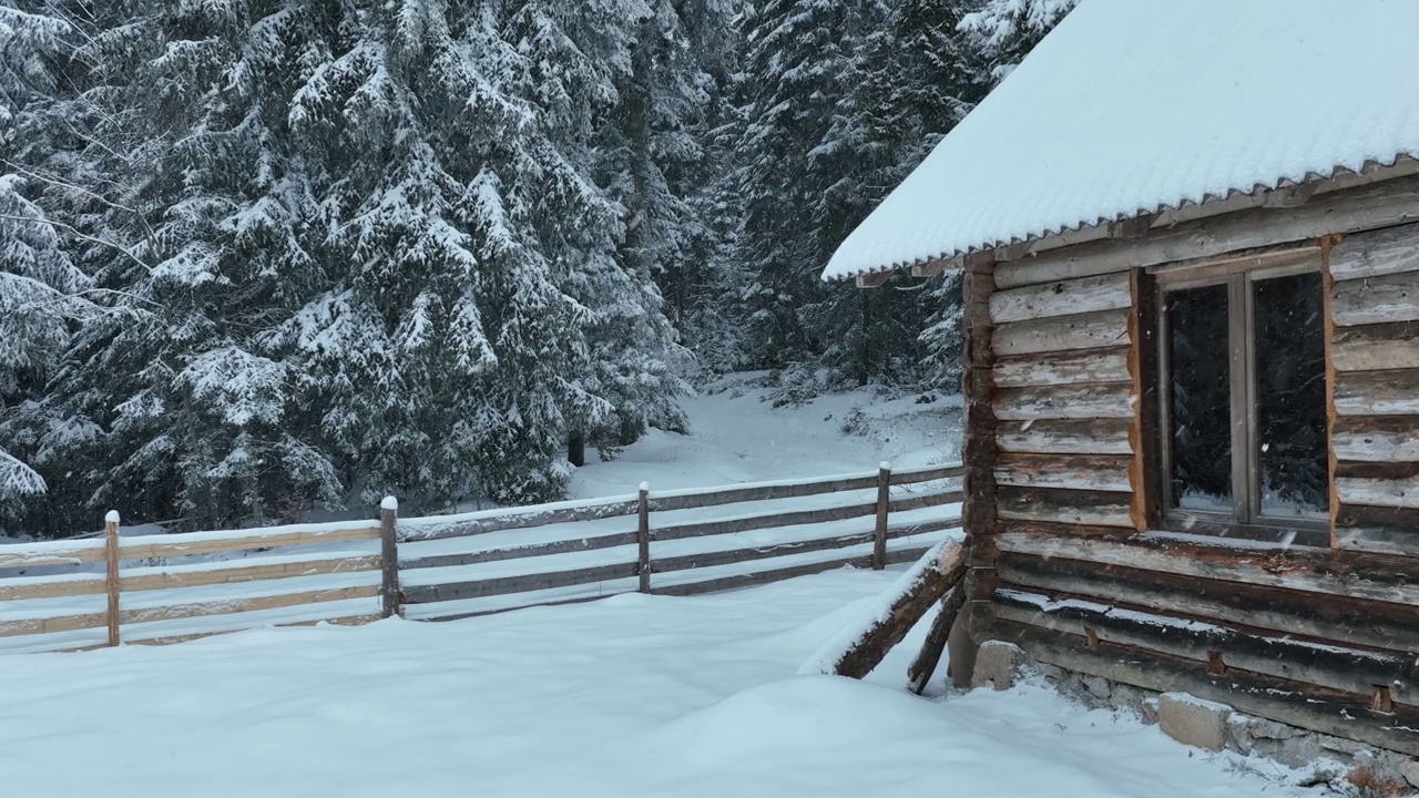 壮丽的山区冬季景观，冷杉林中幽静的小木屋在下雪时完全被雪覆盖。视频素材