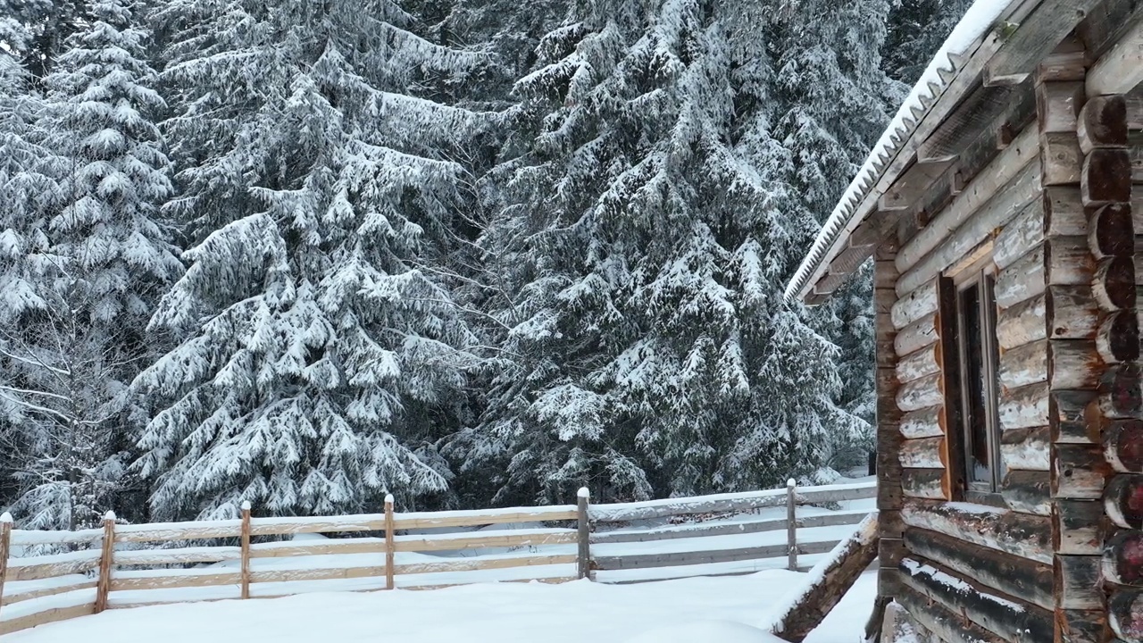 壮丽的山区冬季景观，冷杉林中幽静的小木屋在下雪时完全被雪覆盖。视频素材