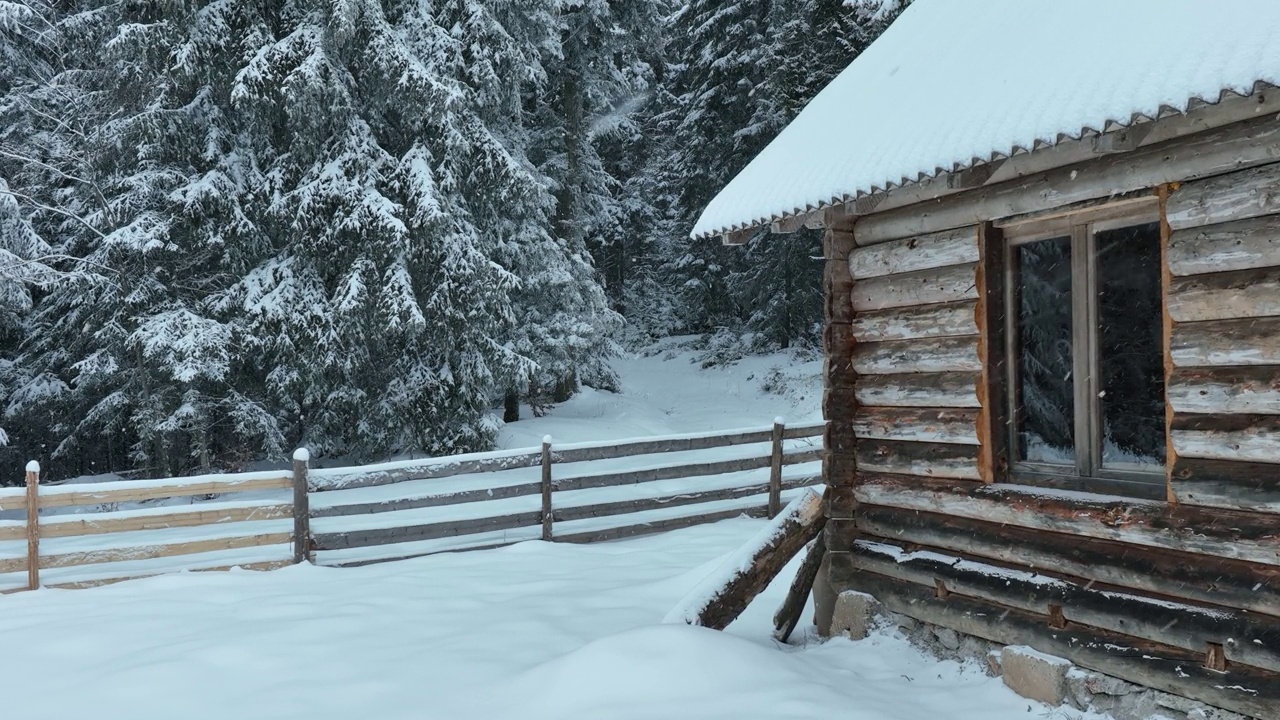 壮丽的山区冬季景观，冷杉林中幽静的小木屋在下雪时完全被雪覆盖。视频素材