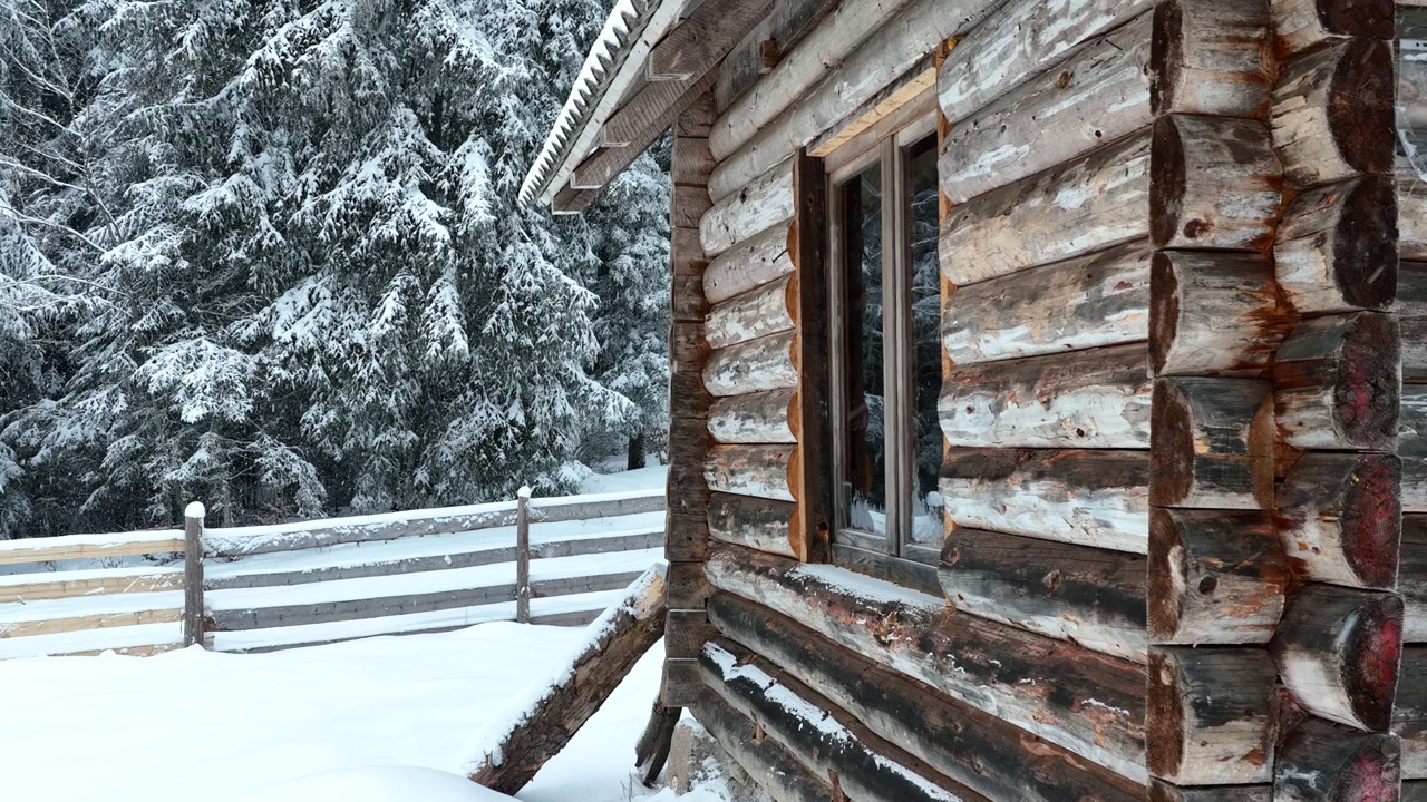 壮丽的山区冬季景观，冷杉林中幽静的小木屋在下雪时完全被雪覆盖。视频素材