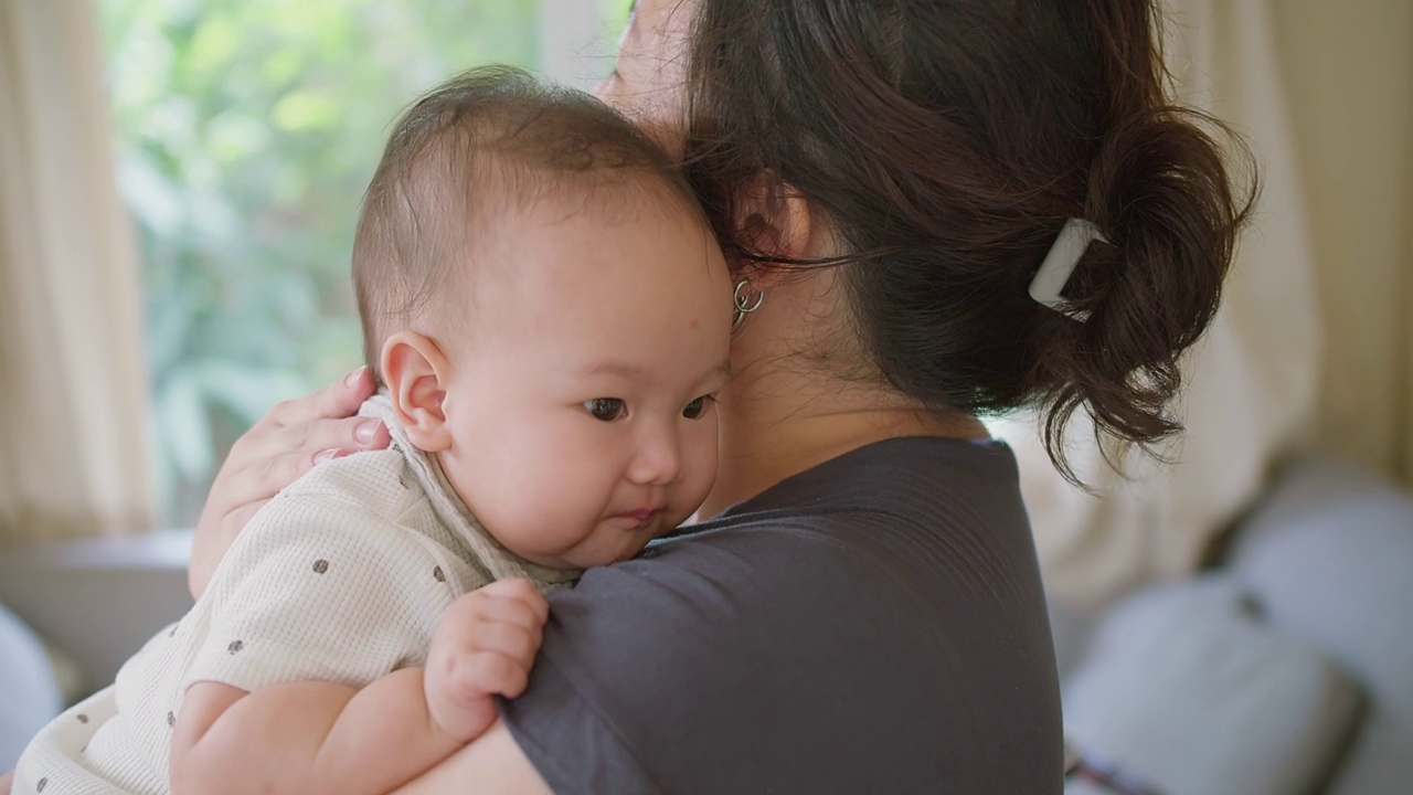 近距离肖像年轻妈妈抱抱抱抱小女婴可爱的小婴儿学步，可爱的亚洲妈妈抱抱小婴儿孩子，放松享受温柔的家庭时刻母性概念视频素材