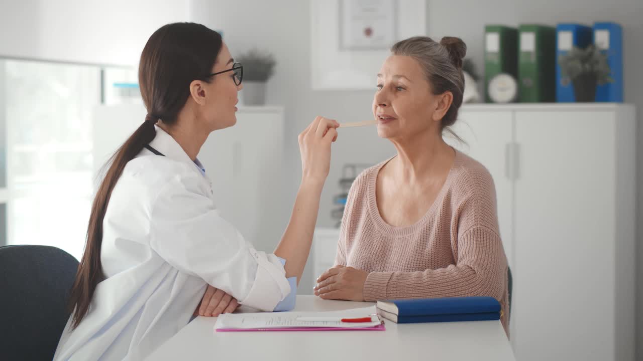 女医生在诊所会诊时检查老年患者的喉咙视频素材