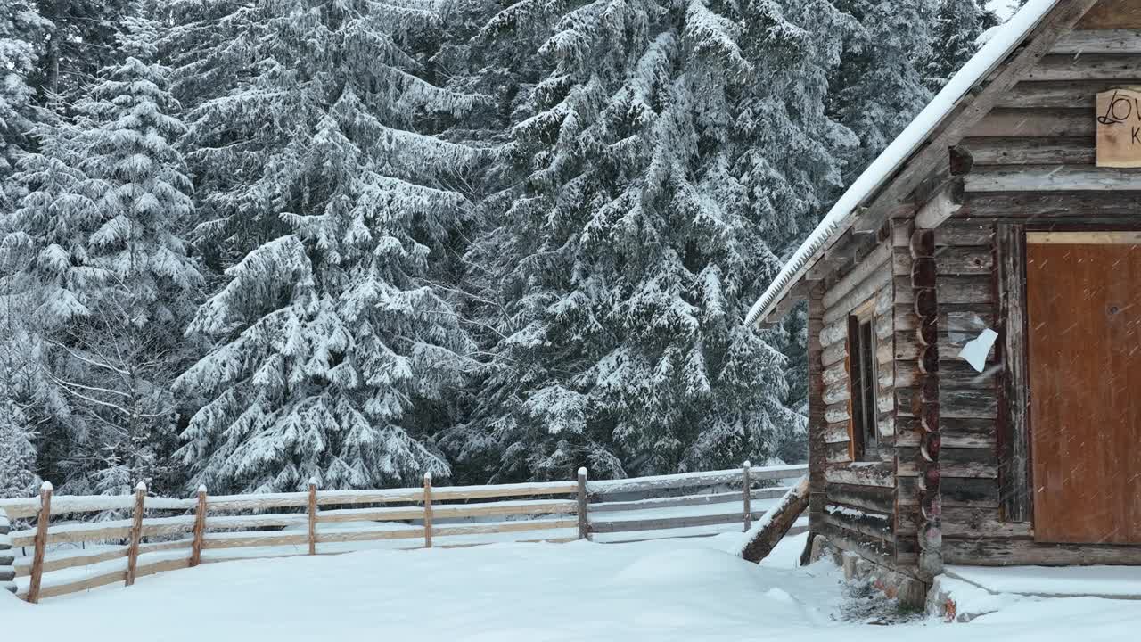 壮丽的山区冬季景观，冷杉林中幽静的小木屋在下雪时完全被雪覆盖。视频素材